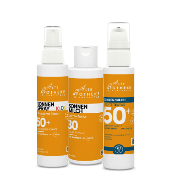 Lächelnde Person trägt Gesichtscreme auf die Wange auf.